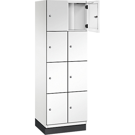 Weißer Schrank mit mehreren Fächern. Ein Fach ist geöffnet. Schwarzer Sockel. Kleine Knöpfe.