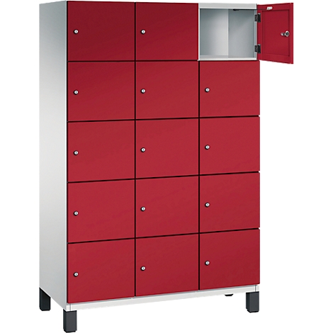 Roter Schrank mit 12 Fächern, ein Fach ist geöffnet. Der Schrank steht auf schwarzen Füßen.