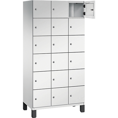 Weißer Schrank mit 16 Fächern, ein Fach geöffnet. Schwarze Füße.