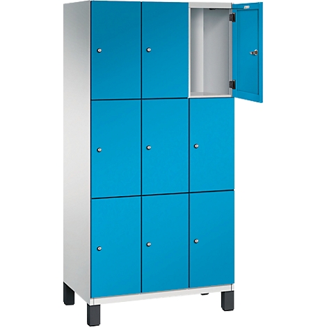 Schrankwand mit blauen Türen, eine Tür geöffnet. Der Schrank steht auf schwarzen Füßen.