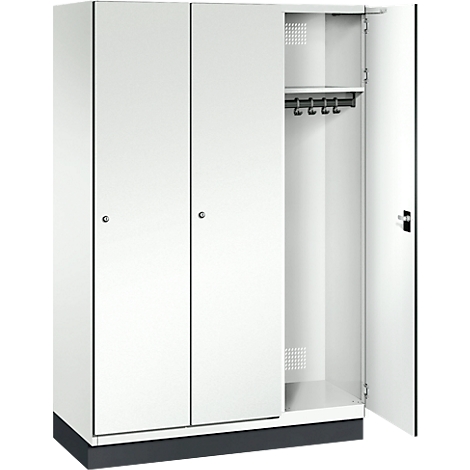 Weißer Stahlschrank, eine Tür offen, mit Kleiderstange. Schrank steht auf grauem Sockel.