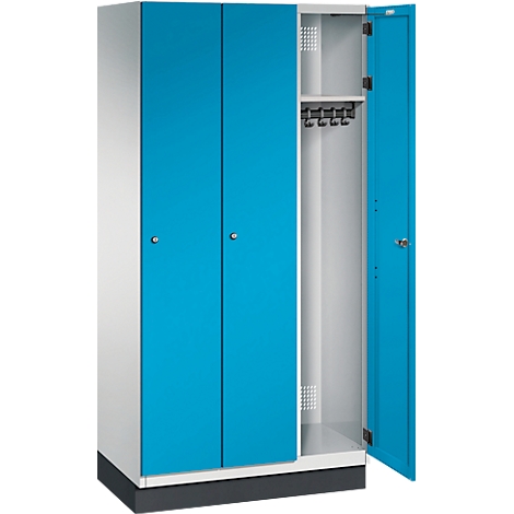 Ein blauer und weißer Stahlschrank, eine Tür geöffnet. Im Inneren sind Haken für Kleidung sichtbar.