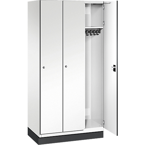 Weißer Metallspind mit zwei geschlossenen Türen und einer geöffneten Tür, in der Haken und ein Regal zu sehen sind.