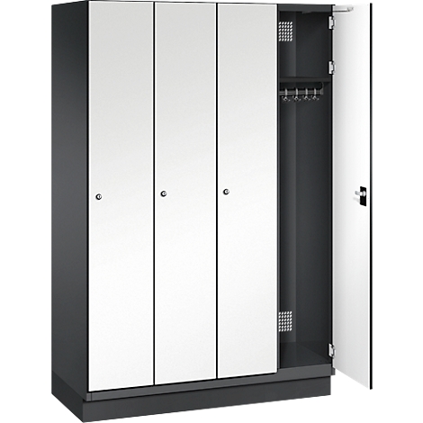 Dreitüriger Spind, eine Tür geöffnet. Weiße Türen, schwarzer Rahmen. Im offenen Fach: Kleiderbügel, Gitter.