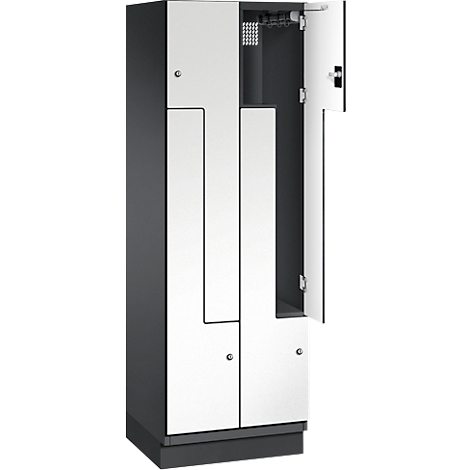 Ein grauer Spind mit weiß gestrichenen Türen, eine Tür ist geöffnet. Eine Kleiderstange ist im Inneren zu sehen.