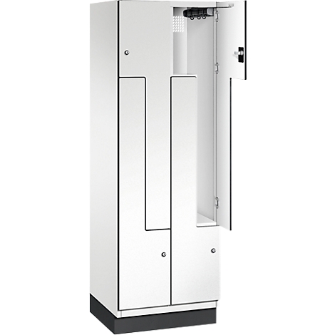 Weißer Spind mit offener Tür, schwarzer Sockel, dahinter Kleiderhaken.