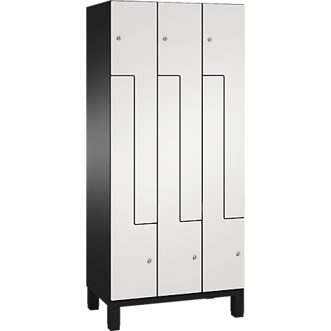 Ein hoher, weißer Schrank mit schwarzen Akzenten, Füßen und einer einzigartigen Frontgestaltung.