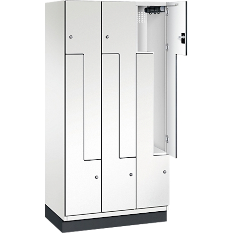 Weißer Schrank mit geöffneter Tür. Einzelne Fächer mit schwarzer Umrandung, silberfarbene Knöpfe.