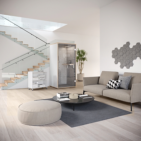 Salon moderne avec une cabine téléphonique insonorisée. Un escalier et un canapé en arrière-plan.