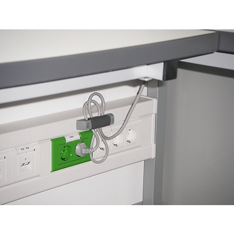 Close-up of a power strip with cable holder and plugged-in plug.