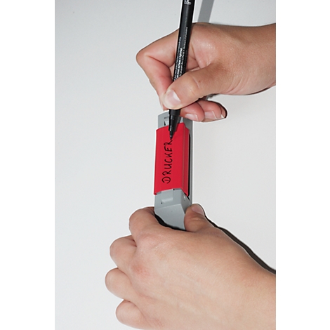 Person writing on a red sticker with a black pen. The sticker says "DRUCKER".