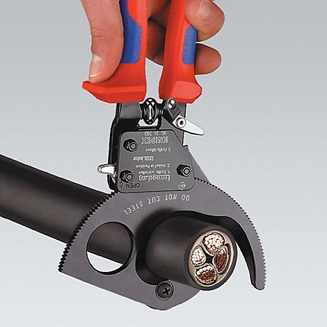 A hand holds Knipex cable stripper pliers, cutting through cable insulation and exposing the inner wires.