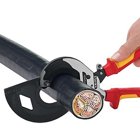 A person uses red and yellow Knipex cable shears to cut a thick, black cable. The inner workings of the cable are visible.