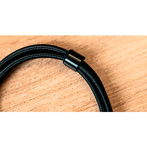 Gros plan d'un câble tressé noir avec un connecteur cylindrique sur une surface en bois.