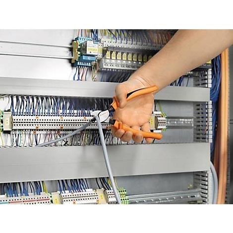 Hand with orange pliers fixing a grey cable to an electrical installation.