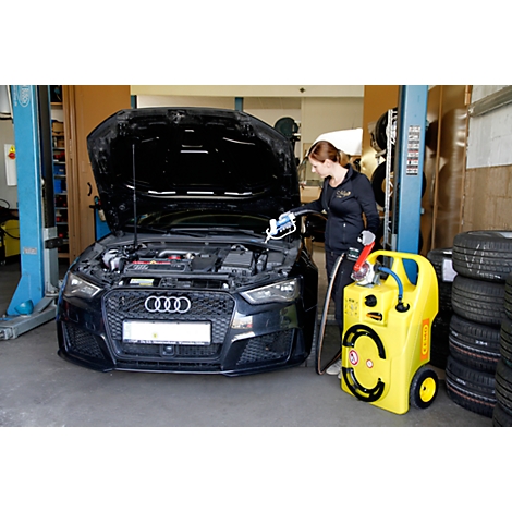 Een vrouw in een werkplaats vult een zwarte Audi met open motorkap met een geel apparaat.