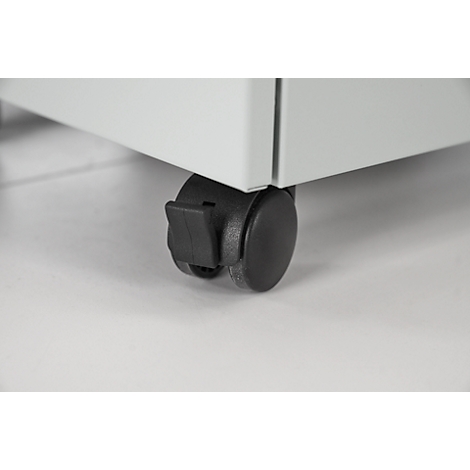 Gros plan d'une roulette noire sous un meuble blanc, détails.