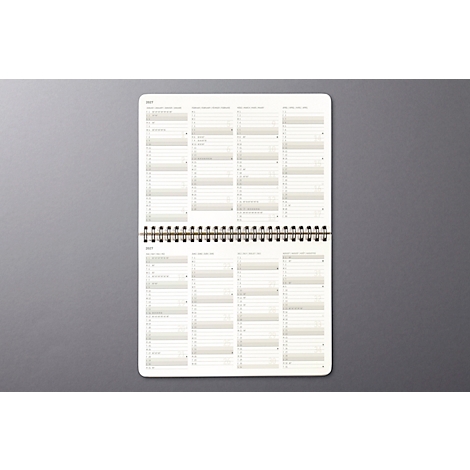 Cahier ouvert avec aperçus mensuels. Fond gris.