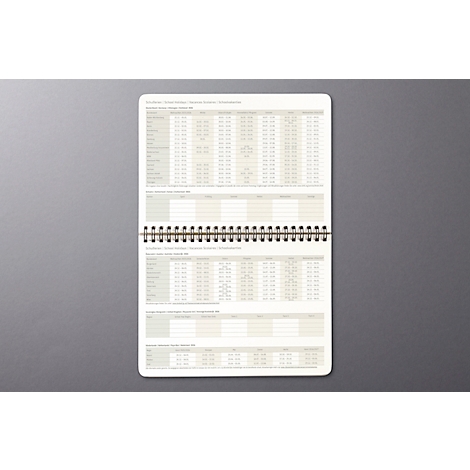Bloc-notes à spirale. Les pages sont remplies de tableaux et de colonnes.