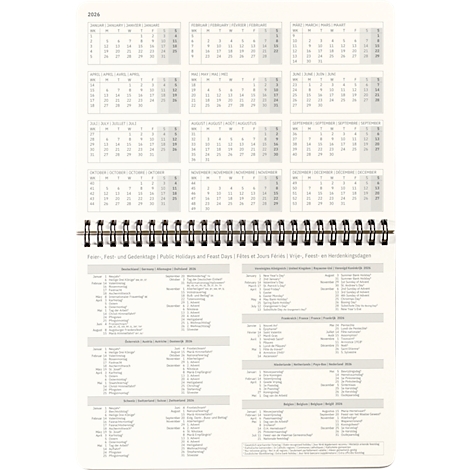 Un calendrier blanc avec reliure spirale, vues mensuelles et aperçu des jours fériés.