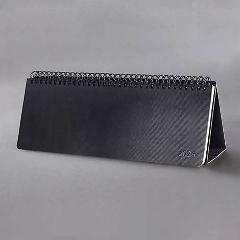 Calendrier de bureau noir avec reliure spirale, fond gris. Impression "2026".
