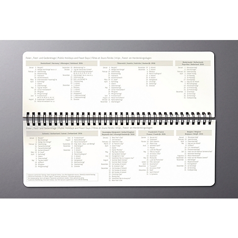 Carnet ouvert avec des tableaux. Les pages sont imprimées avec du texte gris, comprenant des jours fériés et des fêtes.