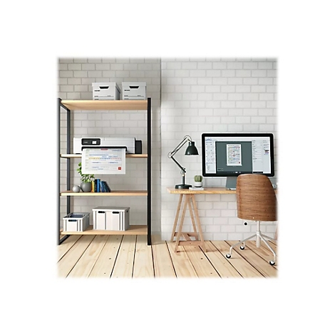 Ein Arbeitsplatz mit Computer, Drucker und Büromaterialien vor einer Backsteinwand.