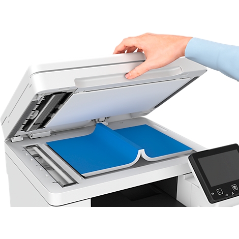 Een hand opent het deksel van een scanner. Daaronder ligt blauw papier.