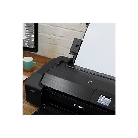Schwarzer Canon-Drucker mit Papierauswurf. Auf dem Bedienfeld steht "Ready to print". Im Hintergrund: Schreibtisch, Bildschirm, Tasse.