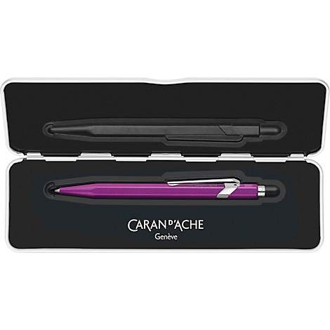 Pens in an open white box: black on top, pink below. Text "CARAN D'ACHE Geneve".