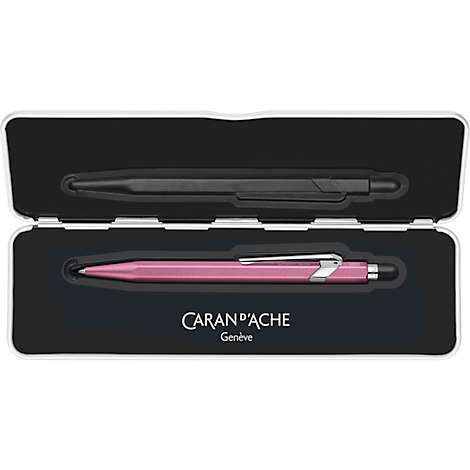 Opened silver pen box with a black and a pink ballpoint pen. The logo "CARAN D'ACHE Genève" is at the bottom.