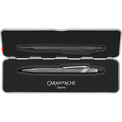 Offene schwarze Metalldose mit zwei Stiften. Oben ein schwarzer Stift, unten ein silber-grauer Stift mit Clip.