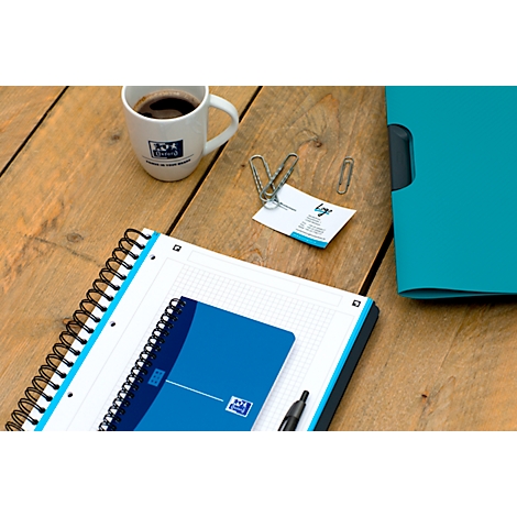 Table en bois avec blocs-notes, stylo, trombones, carte de visite et tasse à café.