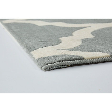 Close-up of a gray carpet with a white, curved pattern. The edge is rolled up.