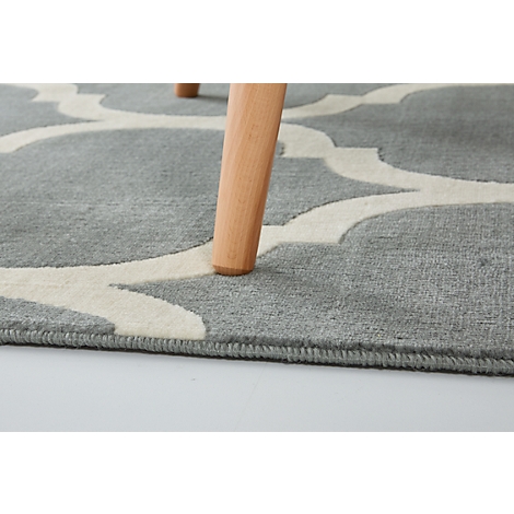 Gray carpet with white pattern, wooden leg, close-up.