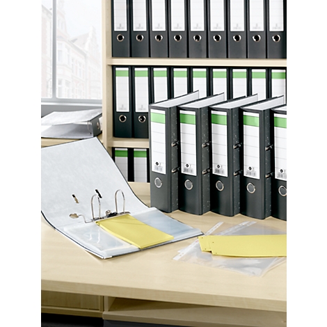 Carpetas negras de archivos de pie y acostadas en un escritorio de madera. En el fondo, hay más carpetas en un estante.