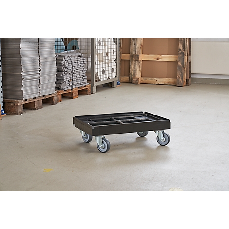 Carro de transporte negro sobre cuatro ruedas, en un almacén.