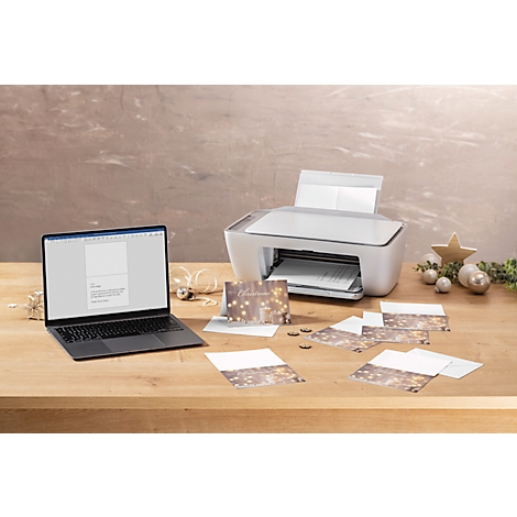 Ordinateur portable avec carte de Noël, imprimante et décorations sur bois. Des cartes sont imprimées.