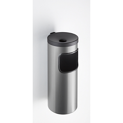 Poubelle cylindrique en métal fixée à un mur blanc. Elle a une ouverture ronde sur le dessus et une fente noire pour les déchets.