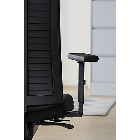Gros plan sur une chaise de bureau noire. L'accent est mis sur l'accoudoir et le dossier, qui est fait de lattes.