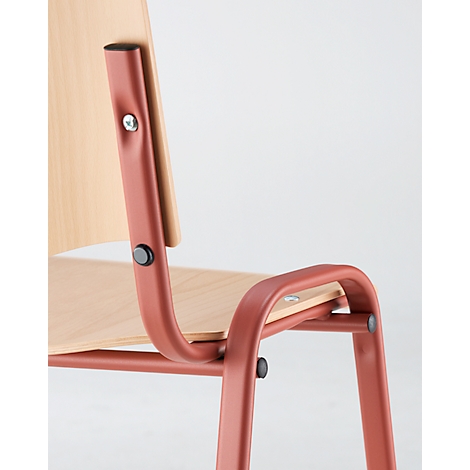 Gros plan sur une chaise avec des pieds en métal rouge et un dossier en bois. L'accoudoir et les détails de la construction sont visibles.