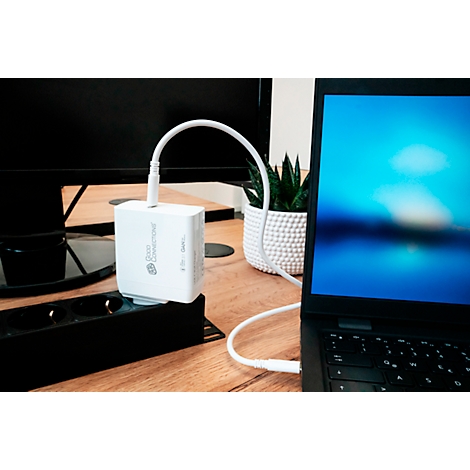 Un chargeur blanc alimente un ordinateur portable. Il repose sur une prise multiple noire et est connecté avec un câble blanc.