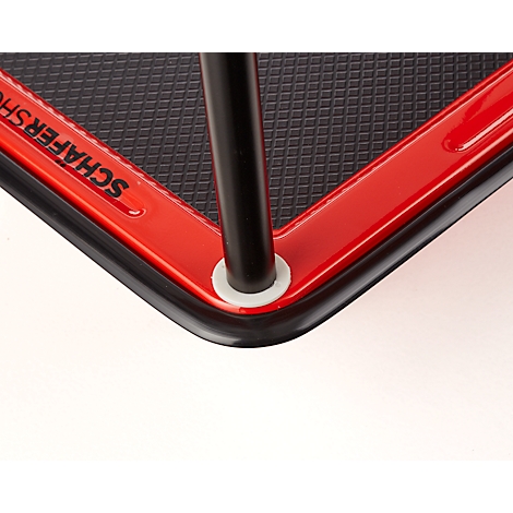 Détail d'un objet rouge, angulaire avec une surface noire et un pied en métal noir. Caoutchouc angulaire noir. Texte "SCHAFERSHOP"