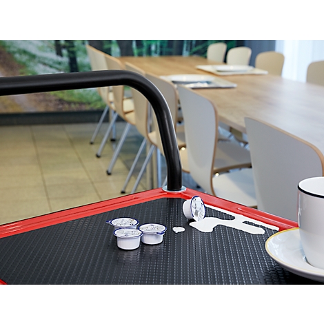 Récipients de crème à café sur un chariot rouge avec du lait renversé. En arrière-plan, une table avec des chaises.