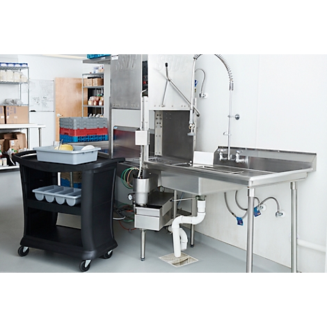 Évier industriel avec pistolet pulvérisateur, à côté d'un chariot de service noir. Le fond est une cuisine.