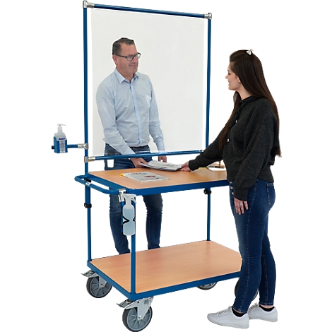 L'homme remet une brochure à une femme. Chariot de comptoir avec protection hygiénique, distributeur de désinfectant.