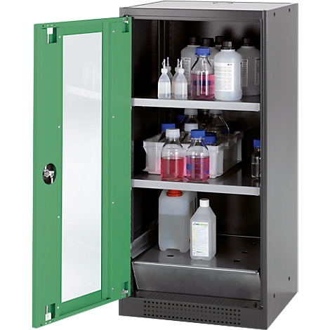 Cabinet with chemicals in a lab. Green door, open door, several bottles and containers on the shelves.