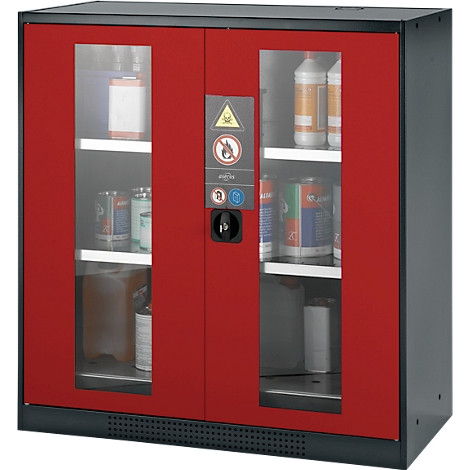 Red safety cabinet with glass windows and hazardous material labeling. Cans and canisters are visible on the shelves.