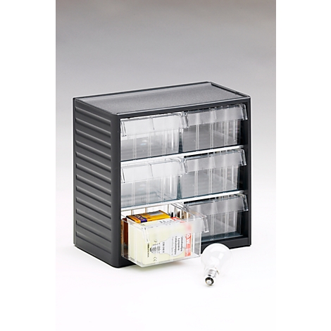 Black cabinet with three drawers. One drawer is open, filled with various items. Next to it is a light bulb.