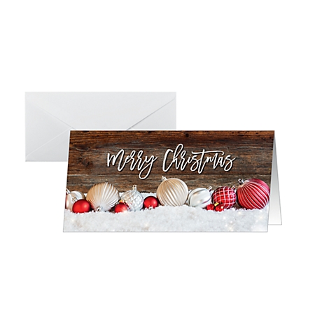 Christmas card with "Merry Christmas" text, Christmas balls and snow on wood effect. Next to it a white envelope.